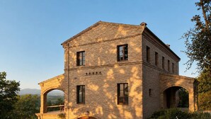 A two-story brick building with a central arched entrance, multiple windows, and a stone pathway leading to the entrance. - Villa Santa Maria dell'Olmo (MORESCO)
