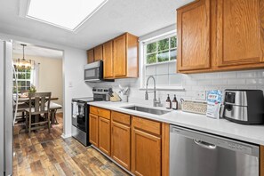 A modern kitchen with wooden cabinets, stainless steel appliances, and a skylight. - Mountain City Hideaway - Downtown Asheville Retreat with Game Room, Deck + Grill (Asheville)