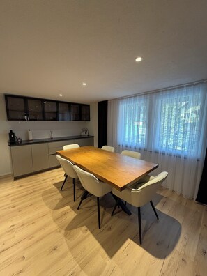 Une cuisine moderne avec une table à manger en bois et des chaises blanches.