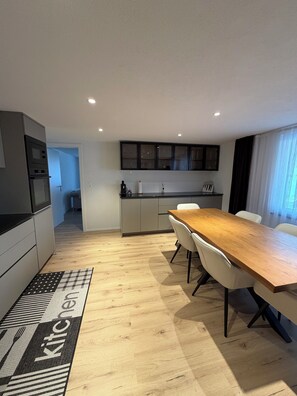 Une cuisine moderne avec un coin repas, un plancher en bois et un tapis de cuisine.
