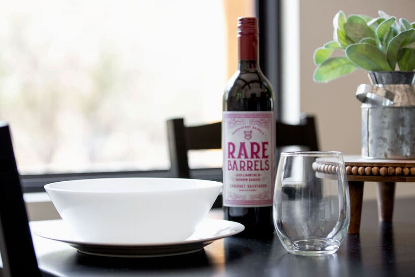 A dining table with a wine bottle, a glass, and a bowl.