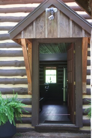 Une cabane en bois avec une porte donnant sur un espace intérieur.