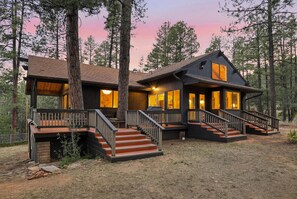 A cabin with a deck, stairs, and a view of the surrounding forest. - Pine Society: fire pit, exchange library, bordering National Forest. (Pine)