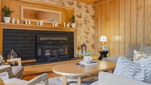 Ein gemütliches Wohnzimmer mit Kamin, Holzwänden, einer Couch und einem Couchtisch.
