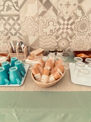A buffet table with bread, pastries, and blue cups. - Etna Rooftop - Panoramic penthouse in Trecastagni with unique view of Etna (Trecastagni)
