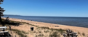 Ein Strand mit Sand, Gras und blauem Himmel.