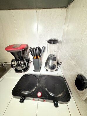 Eine Küche mit Kaffeemaschine, Mixer und einem Herd mit zwei Kochfeldern.