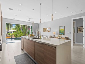A modern kitchen with a large island, built-in appliances, and a view of a pool. - Heated Pool Modern Spacious Waterway Home Offering Comfort Style and Total Relaxation (Wilton Manors)