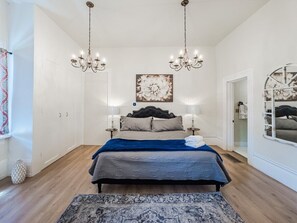 Una camera da letto con un letto, due lampadari, un quadro di grandi dimensioni e uno specchio.