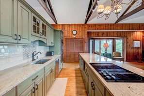 A kitchen with a large island, wooden cabinets, a built-in oven, and a clock on the wall. - Celestial View (Blowing Rock)