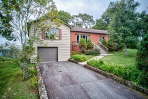 A two-story house with a garage, a front yard with a lawn, and a staircase leading to the front door. - Celestial View (Blowing Rock)