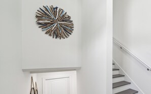 Una escalera con una pared blanca y un elemento decorativo de madera en la parte superior.