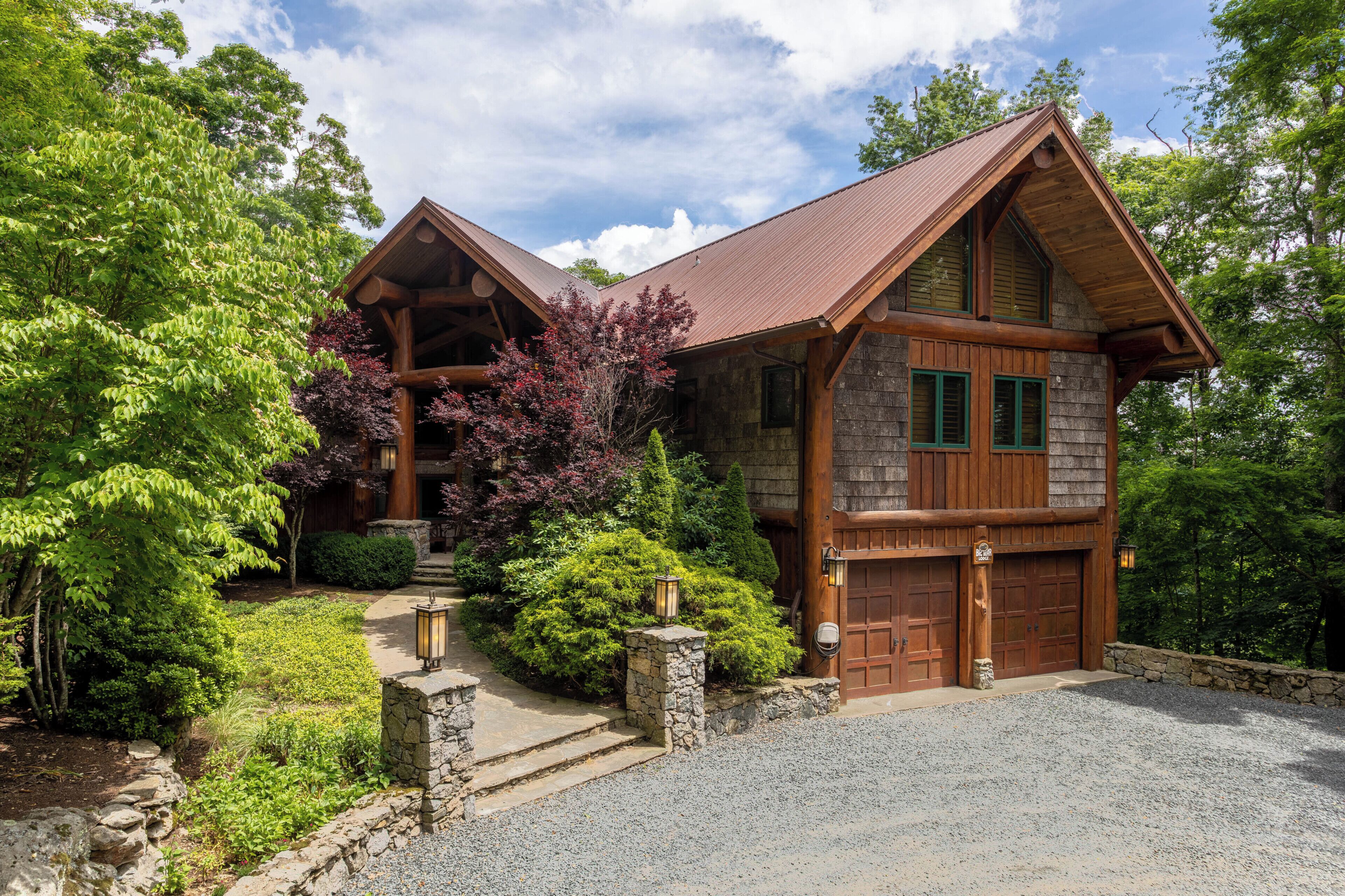 A log cabin with a stone foundation, wooden exterior, and a steeply pitched roof.