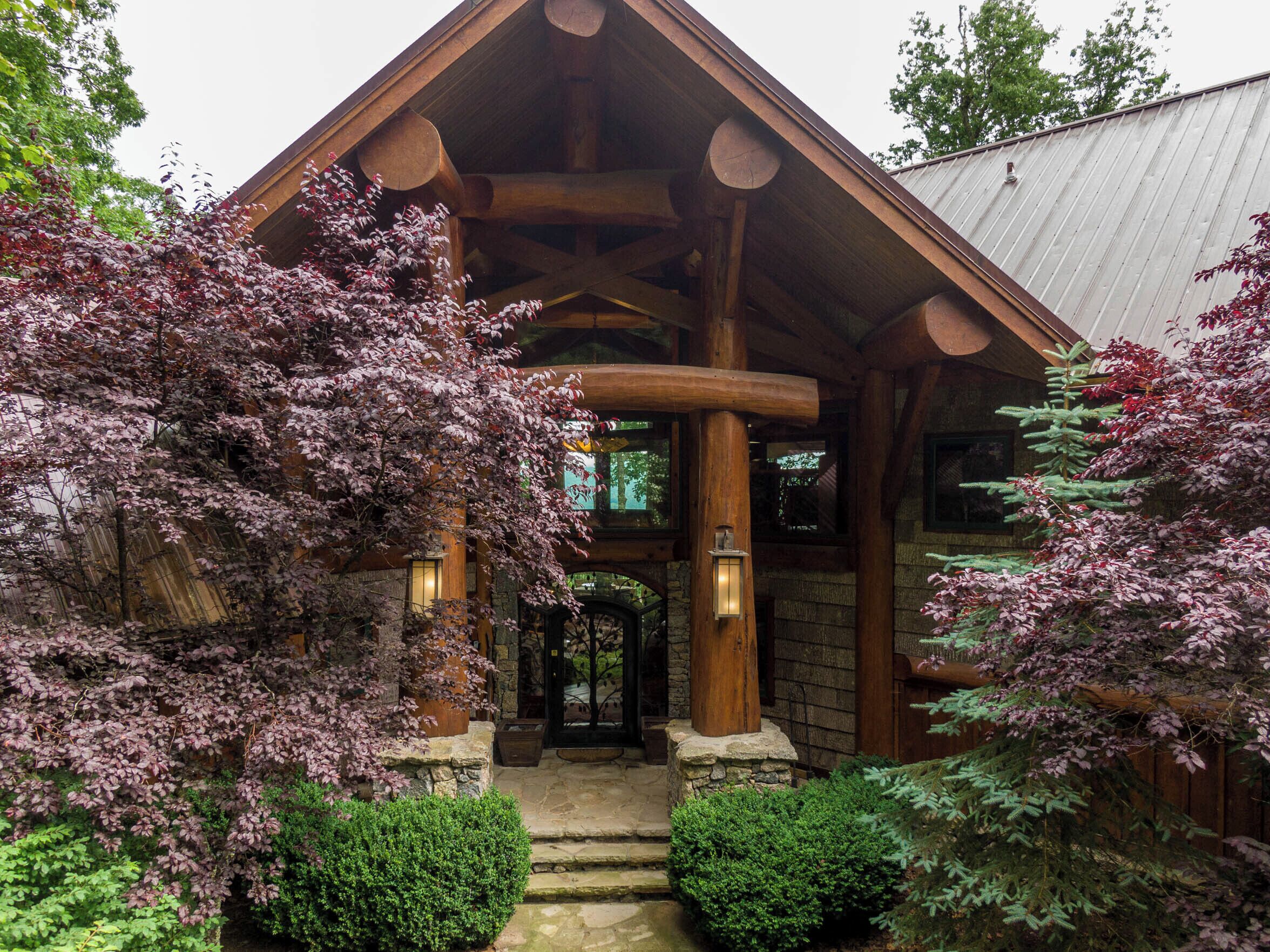 A log cabin with a stone foundation, wooden beams, and a covered porch.