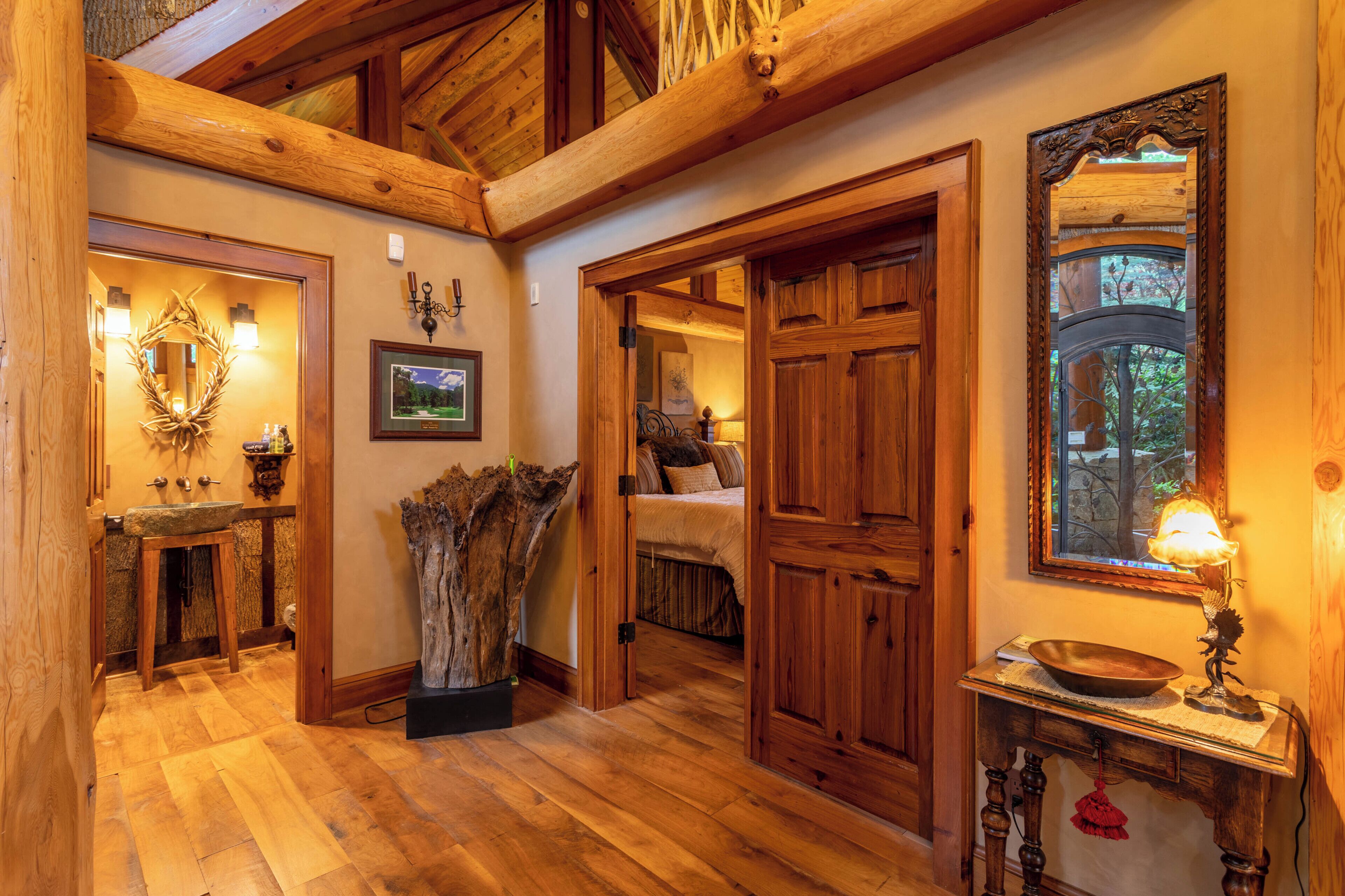 A wooden interior with a large mirror, a wooden bench, and a rustic decor including a tree stump.