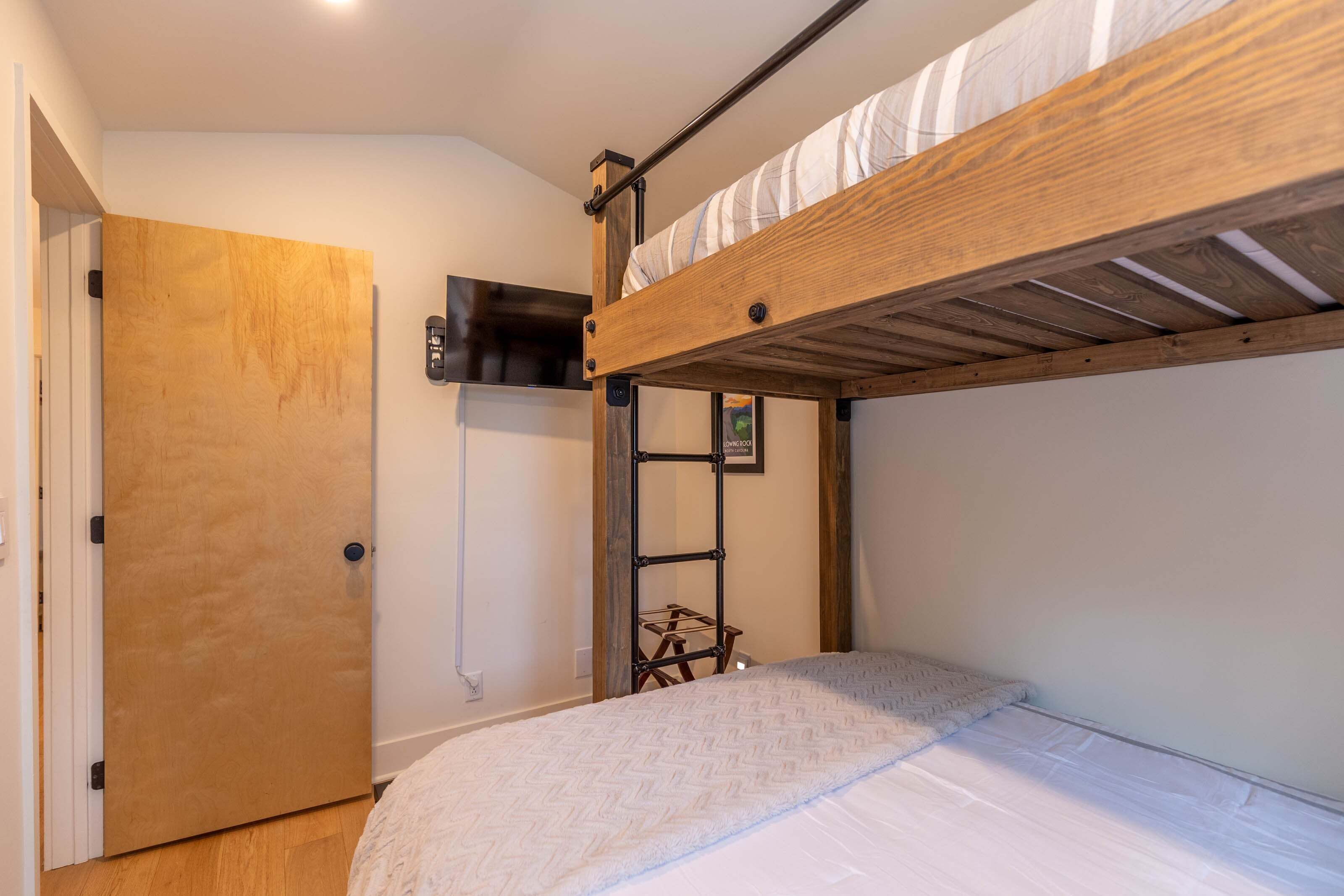 Un lit superposé avec une structure en bois, un matelas blanc et une petite étagère en dessous.