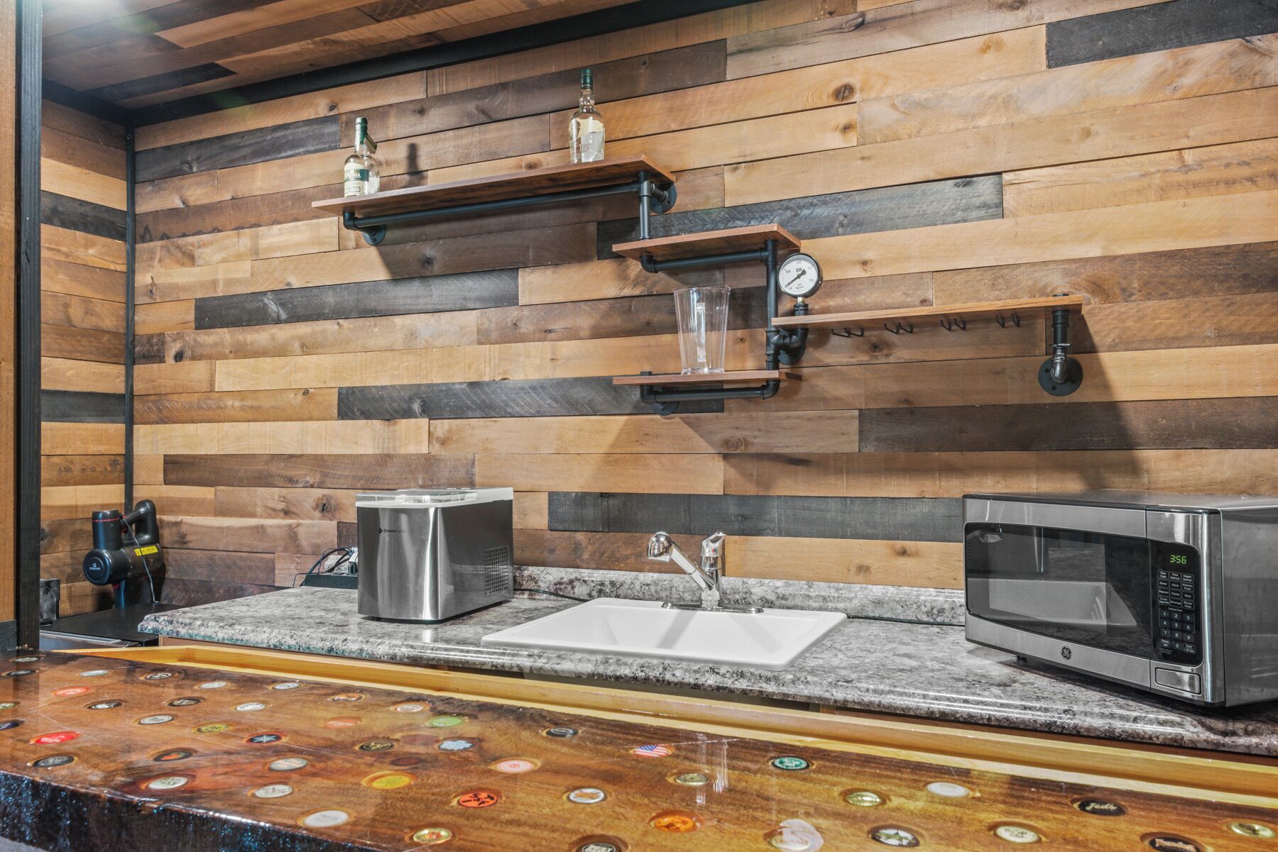 A kitchen with wooden panel walls, a sink, a stove, a microwave, and a coffee machine.