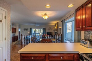 A kitchen with wooden cabinets, a central island, and a dining area with chairs.