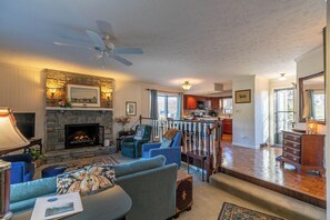 A spacious living room with a fireplace, a dining area, and a kitchen.