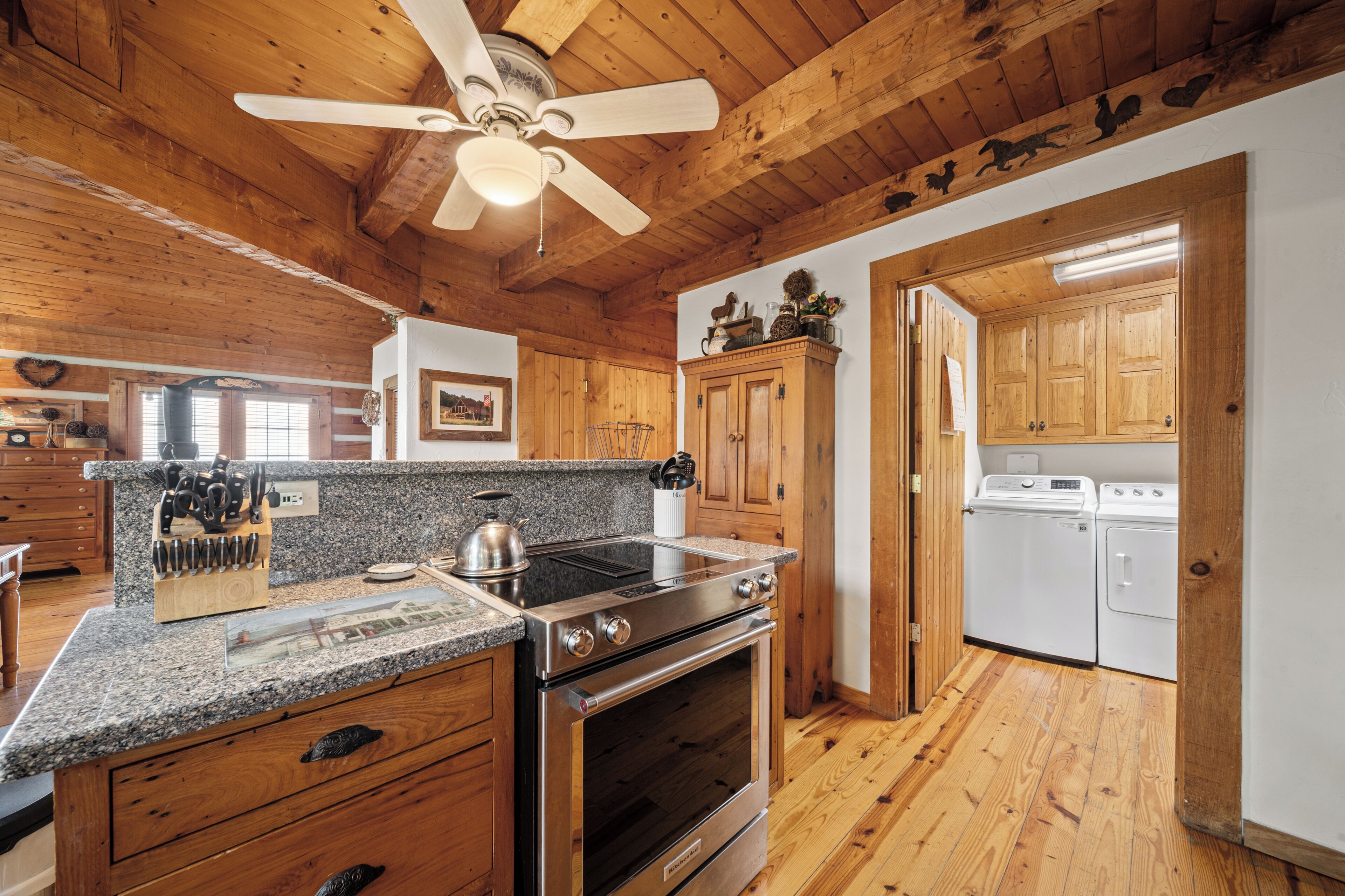 A kitchen with wooden cabinets, a granite countertop, a stove, and a ceiling fan.