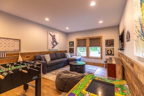 A cozy living room with a foosball table, a sofa, a coffee table, and artwork on the walls. - Howling at the Moon at Eagles Nest (Banner Elk)