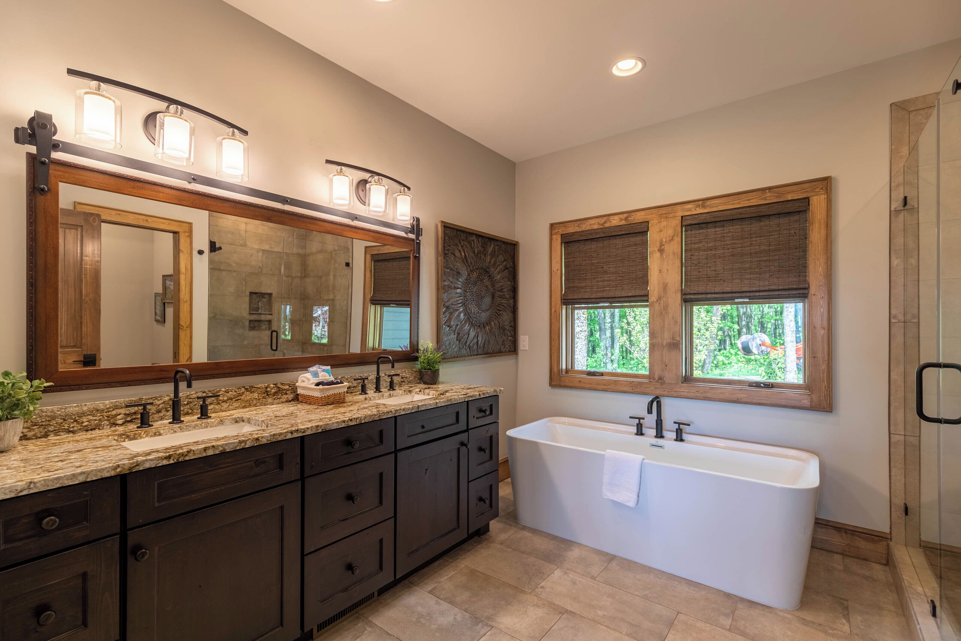 A modern bathroom with a large vanity, a freestanding bathtub, and a large mirror with lights.