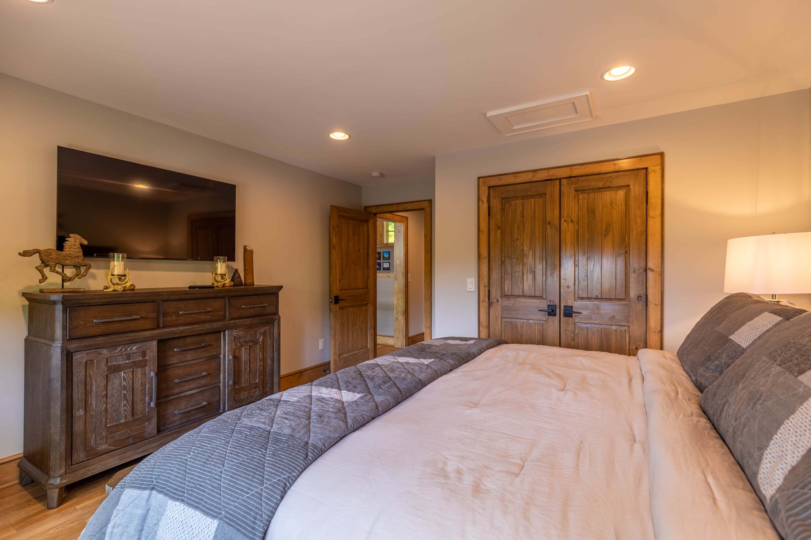 Une chambre à coucher avec un lit, une commode, un miroir et une porte.