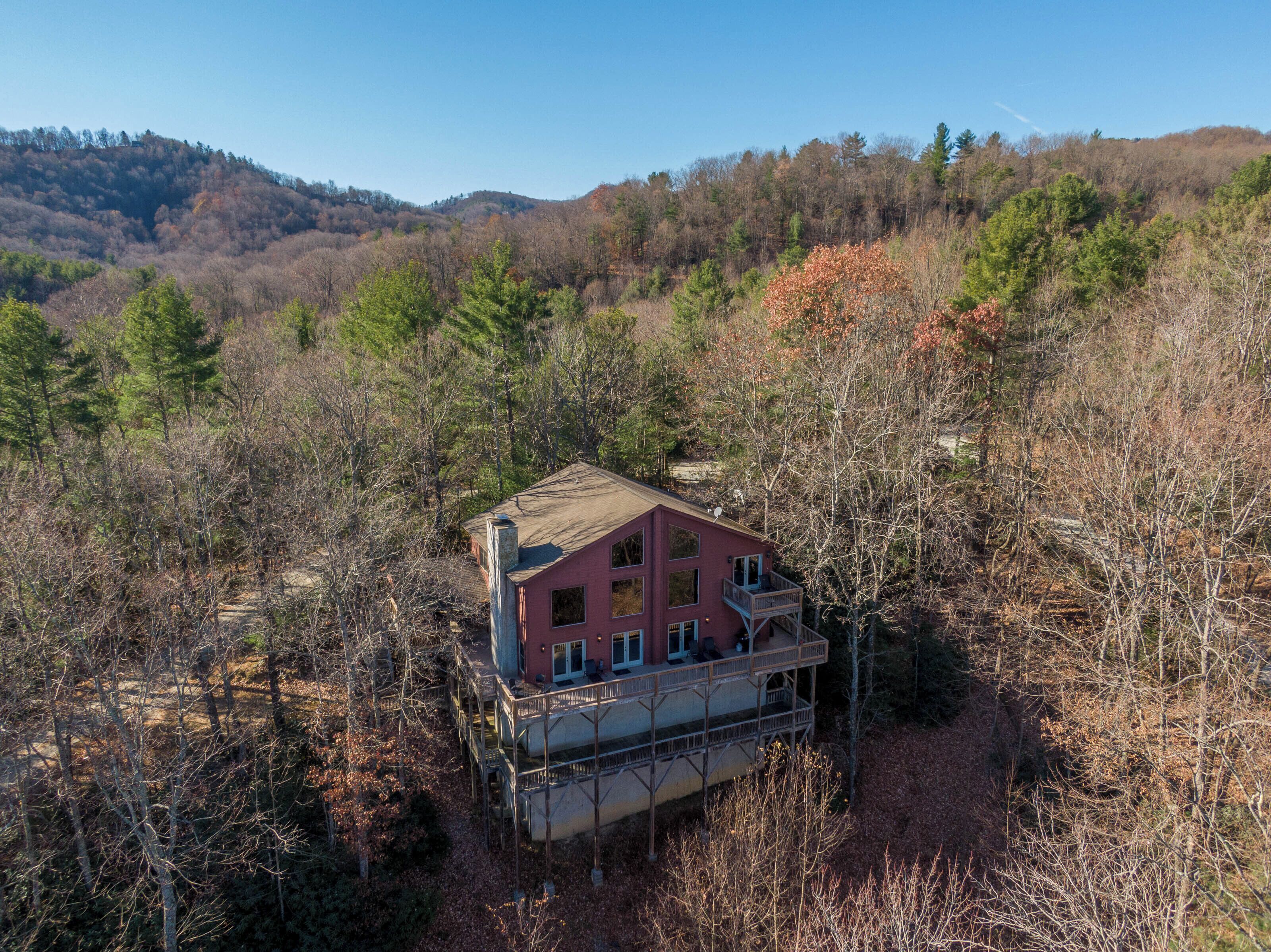 Ein zweistöckiges Haus mit Balkon, umgeben von dichtem Wald und Hügeln.