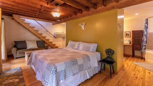 Una camera da letto con un letto, una scala in legno, un divano e un bagno.