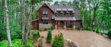 A rustic cabin with a stone foundation, wooden exterior, and a porch with outdoor seating.