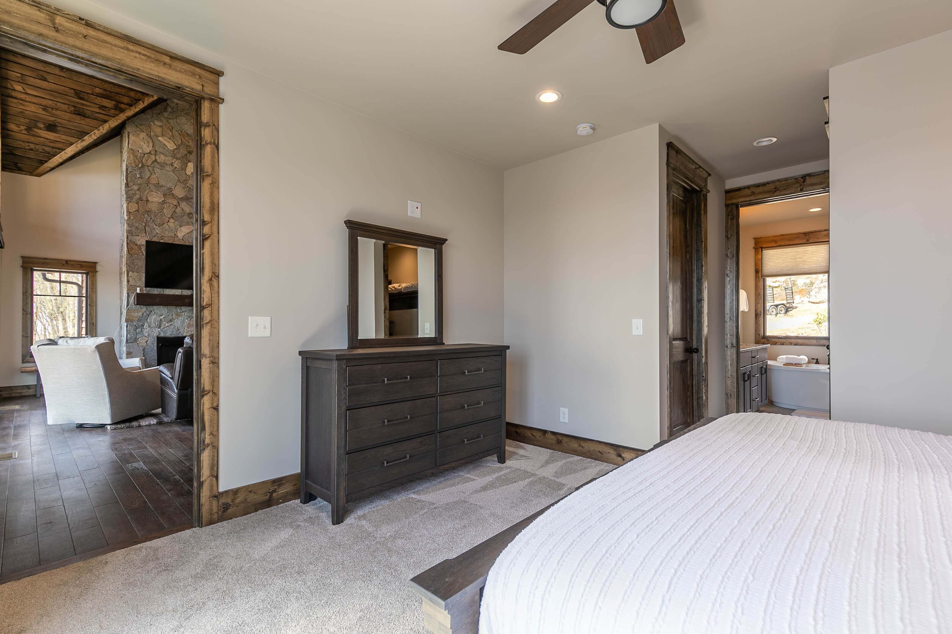 Un dormitorio con cama, cómoda, pared de piedra y vistas al exterior.