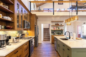 A modern kitchen with wooden cabinets, stainless steel appliances, and a large island with a sink.