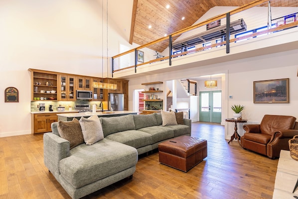 A spacious living area with a large sectional sofa, a leather armchair, and a wooden floor.