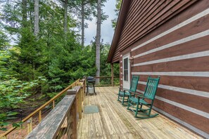 A wooden deck with a grill and chairs, surrounded by trees. - 4J Getaway (Boone)