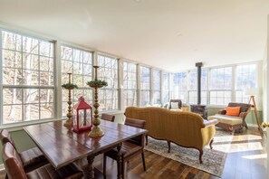 A sunlit room with a dining table, chairs, a sofa, and a fireplace. - Mountain View Retreat (Banner Elk)