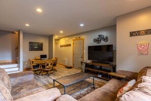 A living room with a TV, sofa, coffee table, wooden dining table, and chairs. - Horse Valley Lodge (Boone)