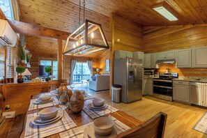 A cozy cabin with a wooden interior, a dining area set for four, and a kitchen with modern appliances. - Horse Valley Lodge (Boone)