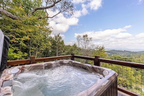 A hot tub with a wooden deck and a scenic view of a forested landscape. - Blue Heaven (Boone)