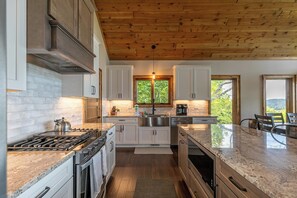 Eine moderne Küche mit weißen Schränken, einer Edelstahlspüle und einer Holzbalkendecke.