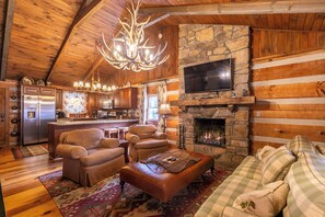 A log cabin interior with a stone fireplace, wooden ceiling, and a modern kitchen. - Riverdale - 4BR With a hot Tub- Near the New River (Boone)