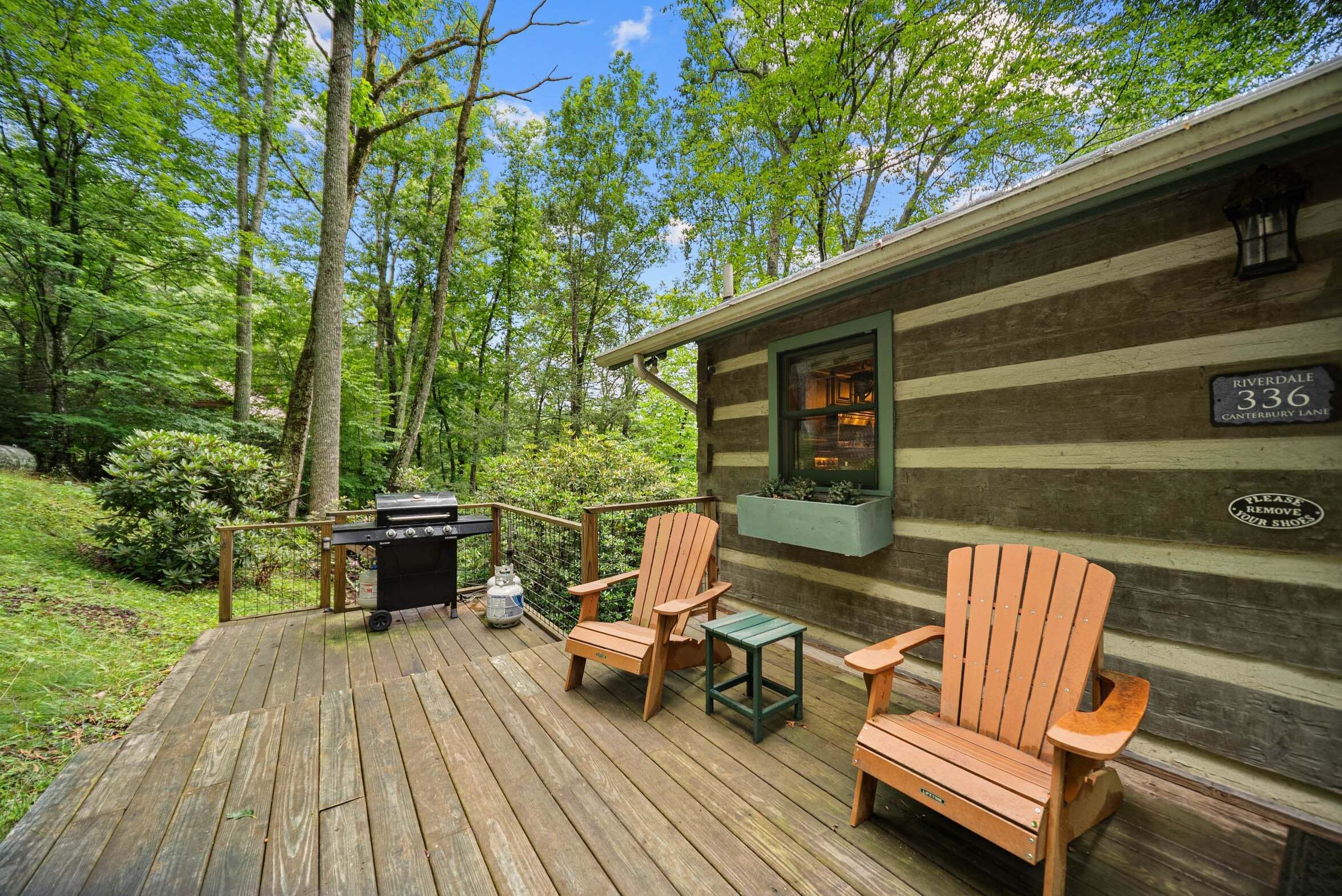 A wooden deck with Adirondack chairs, a grill, and a small table.