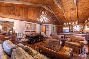 A spacious living area with wooden ceilings, a dining table, and a kitchen in the background. - Riverdale - 4BR With a hot Tub- Near the New River (Boone)