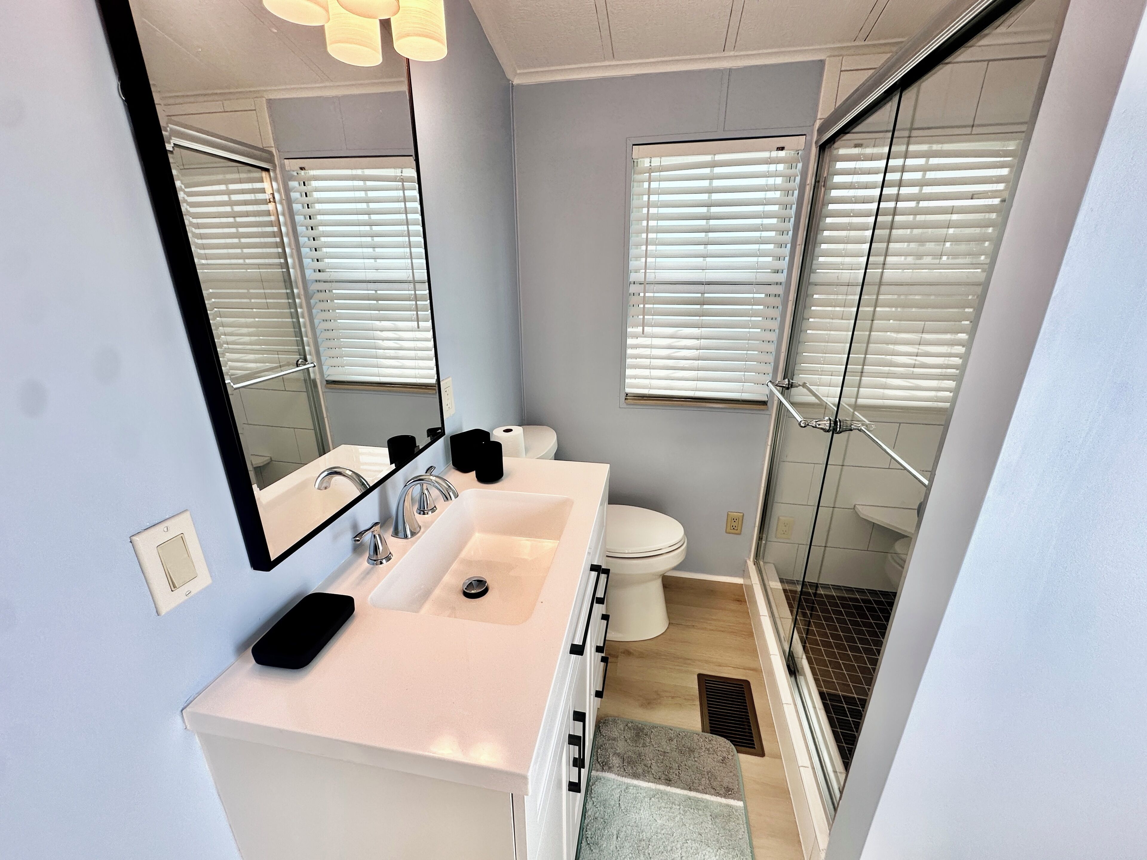Un baño moderno con lavamanos doble, inodoro, cabina de ducha de vidrio y un espejo grande.