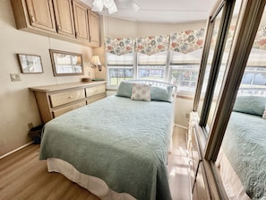 A bedroom with a bed, dresser, window, and floral wallpaper.