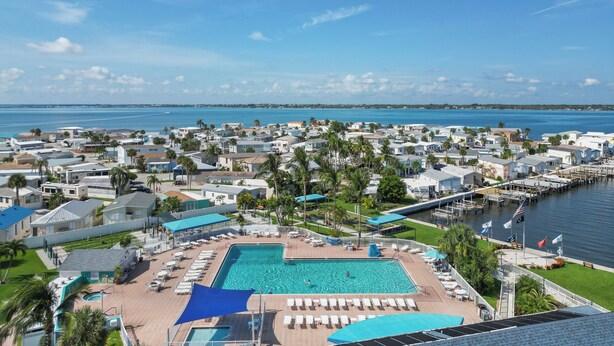 Un resort con una amplia piscina, varias zonas de descanso y un puerto deportivo con barcos.