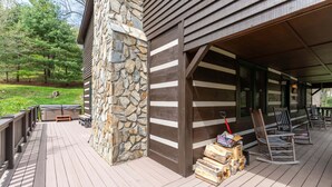 Eine Holzterrasse mit einem Steinpfeiler, eine Veranda mit Stühlen und eine Steinmauer.