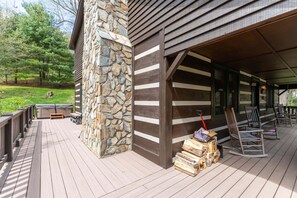 Eine Holzterrasse mit einem Steinpfeiler, eine Veranda mit Stühlen und eine Steinmauer.