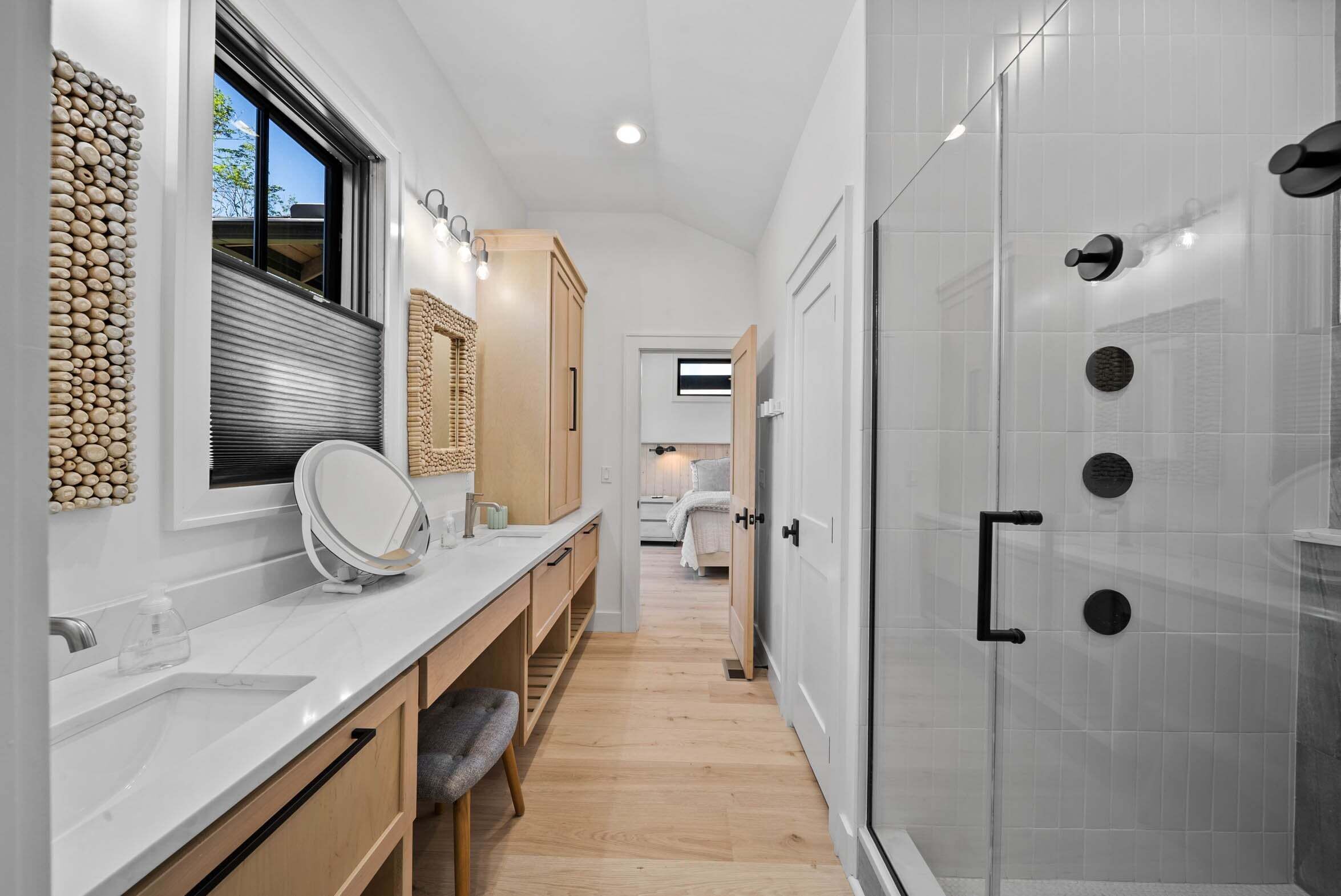 A modern bathroom with a shower, a vanity with a mirror, and a window.