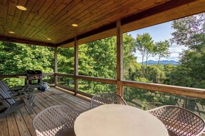 A wooden deck with a table and chairs, overlooking a forested area with mountains in the distance. - Shady Pines (Banner Elk)