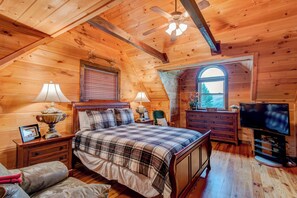 A cozy log cabin bedroom with a bed, two bedside tables, a dresser, a television, and a window with a view. - 1 Awesome Skyview (Vilas)